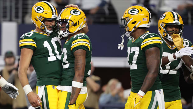 Jordan Love pats Dontayvion Wicks on the head in celebration as two other Packers players stand next to them, too.
